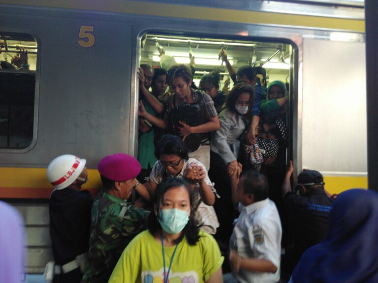 Penumpang menyerbu untuk turun di stasiun Pondok Cina di emplasemen tanpa peron. Tampak Walka dan petugas PT KCJ yang membantu.
