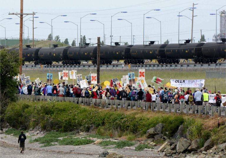 Para aktivis berjalan di samping rel menuju kilang minyak untuk menyuarakan perubahan kebijakan pengelolaan energi | Foto: Scott Terrell via AP